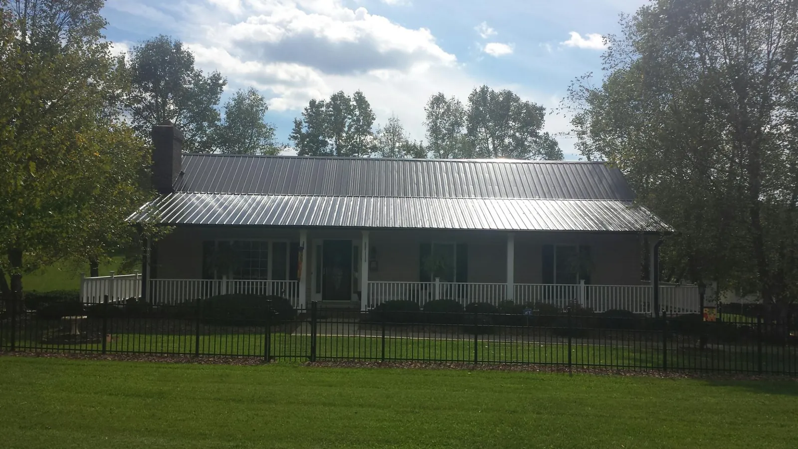 Gray metal roof on a brick ranch with a full width front porch — Gutter Guard Installation work by our crew in Warwick